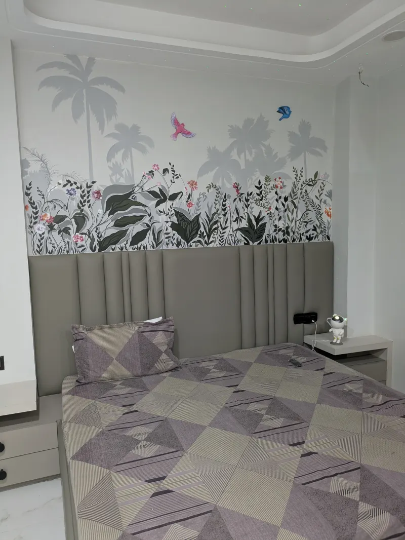 Grey botanical mural painted behind a bed